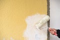 Manual worker paints wall white with painter roller, close-up Royalty Free Stock Photo