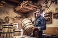 Craftsman puts finished wooden barrel on a table in his rustic workshop