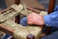 Detail of male hand of craftsman repairs straw chair Royalty Free Stock Photo