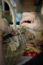 Craftsman`s hands sewing with thread a basket of vegetable fiber Royalty Free Stock Photo