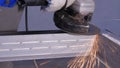 Craftsman sawing metal with disk grinder in workshop. Grinding metal with sparks flying. Electric wheel grinding on Royalty Free Stock Photo