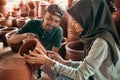 craftsman showing his pottery products to a girl wearing hijab Royalty Free Stock Photo