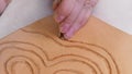 Craftsman stamps an ornament on surface of leather with Beveler Stamping tool