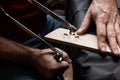 A craftsman uses a fretsaw to cut a string rest from a blank Royalty Free Stock Photo