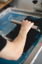 Craftsman using squeegee and plastisol ink while working on screen printing machine