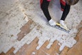 Craftsman in workwear who, using the rabot, removes excess glue left on the floor after removing the wooden parquet glued to the