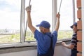 Craftsmen workers install window in house rattle with a special rubber hammer Royalty Free Stock Photo