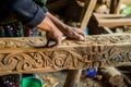 craftsperson carving intricate designs into timber beam