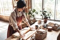 Craftsperson Concept. Young woman making pottery at creative studio standing rolling clay joyful in daylight