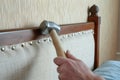 craftsperson using a hammer to secure tacks on a headboard