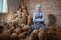 craftswoman in veil sitting among woven water hyacinth crafts