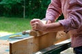 Craftswoman working with planer outdoors, close-up view. Woodworking, furniture production, carpentry concept