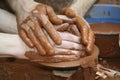 A Craftwoman\'s hands guiding a other hands to teach him to work with the ceramic