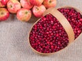 Cranberries in a basket on a fabric background and apples lying next