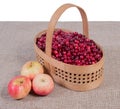 Cranberries in a basket on a fabric background and apples lying next