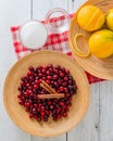 Cranberries and cinnamon sticks on a wooden plate, sugar in a bowl, oranges, orange zest close-up. Ingredients for a cranberry