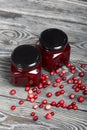 Cranberry jam in glass jars. Cranberries are scattered nearby. On wooden boards with a beautiful texture