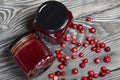 Cranberry jam in glass jars. Cranberries are scattered nearby. On wooden boards with a beautiful texture