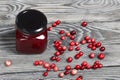 Cranberry jam in glass jars. Cranberries are scattered nearby. On wooden boards with a beautiful texture
