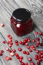 Cranberry jam in glass jars. Cranberries are scattered nearby. On wooden boards with a beautiful texture