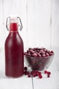 Cranberry juice in a bottle and a cranberries in a glass bowl