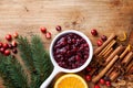 Cranberry sauce in ceramic saucepan with ingredients for cooking decorated with fir tree for Christmas or Thanksgiving day on wood Royalty Free Stock Photo