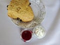 Cranberry scone raspberry jam and cream on a white tablecloth