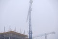 Crane on the background of under construction skyscrapers in a fog on an abandoned Royalty Free Stock Photo