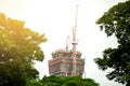 Crane and building construction site against between green tree. Royalty Free Stock Photo