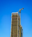 A crane building a modern skyscraper against a blue sky. Construction site. Royalty Free Stock Photo