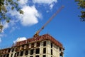 Crane on the building site. Construction of an apartment building, blue sky. Royalty Free Stock Photo