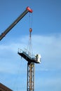 Crane and building under construction against blue sky, closeup photo Crane assembly. Royalty Free Stock Photo