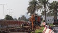 A crane digging the ground and collecting soil on a dumping truck during Highway construction- Doha, Qatar -03/10/2020