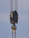 Crane hook with red and white stripes hanging, blue sky in background Royalty Free Stock Photo