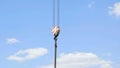 Crane hook with red and white stripes hanging, blue sky in background Royalty Free Stock Photo