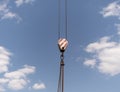 Crane hook with red and white stripes hanging, blue sky in background Royalty Free Stock Photo