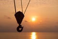 Crane hook silhouette in sunset time with sea background in offs