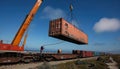 Crane is lifting a large container onto a train Royalty Free Stock Photo