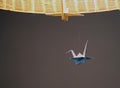 Paper crane hanging under a lampshade