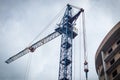 Crane near the brick high-rise building under construction against the blue sky, modern construction Royalty Free Stock Photo