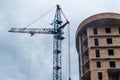 A crane near a multi-storey building under construction against the sky, bottom view. Royalty Free Stock Photo