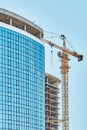 Crane near skyscraper with glass facade at construction site Royalty Free Stock Photo