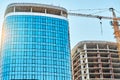 Crane near skyscraper with glass facade at construction site Royalty Free Stock Photo