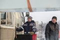 Crane operator in blue jacket and gray hat unloading ice blocks