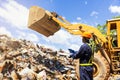 Crane operator. The engineer is controlling the loader to get the iron to recycle. Worker standing in metal landfill outdoors