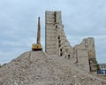 Crane on a pile of rubish next to a half demolished stripped down apartment tower