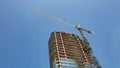 A crane rissing above a new high rise building under construction. Royalty Free Stock Photo