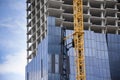 Crane on skyscraper construction site with windows reflecting sky Royalty Free Stock Photo