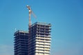 Crane on skyscraper construction site with windows reflecting sky Royalty Free Stock Photo