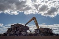 Crane stacking cubes of compressed metal at recycling center